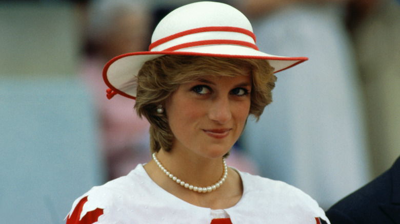 Princess Diana smiles in a white hat with red stripes